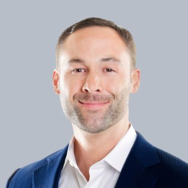 A man in a blue suit and white shirt is smiling for the camera.