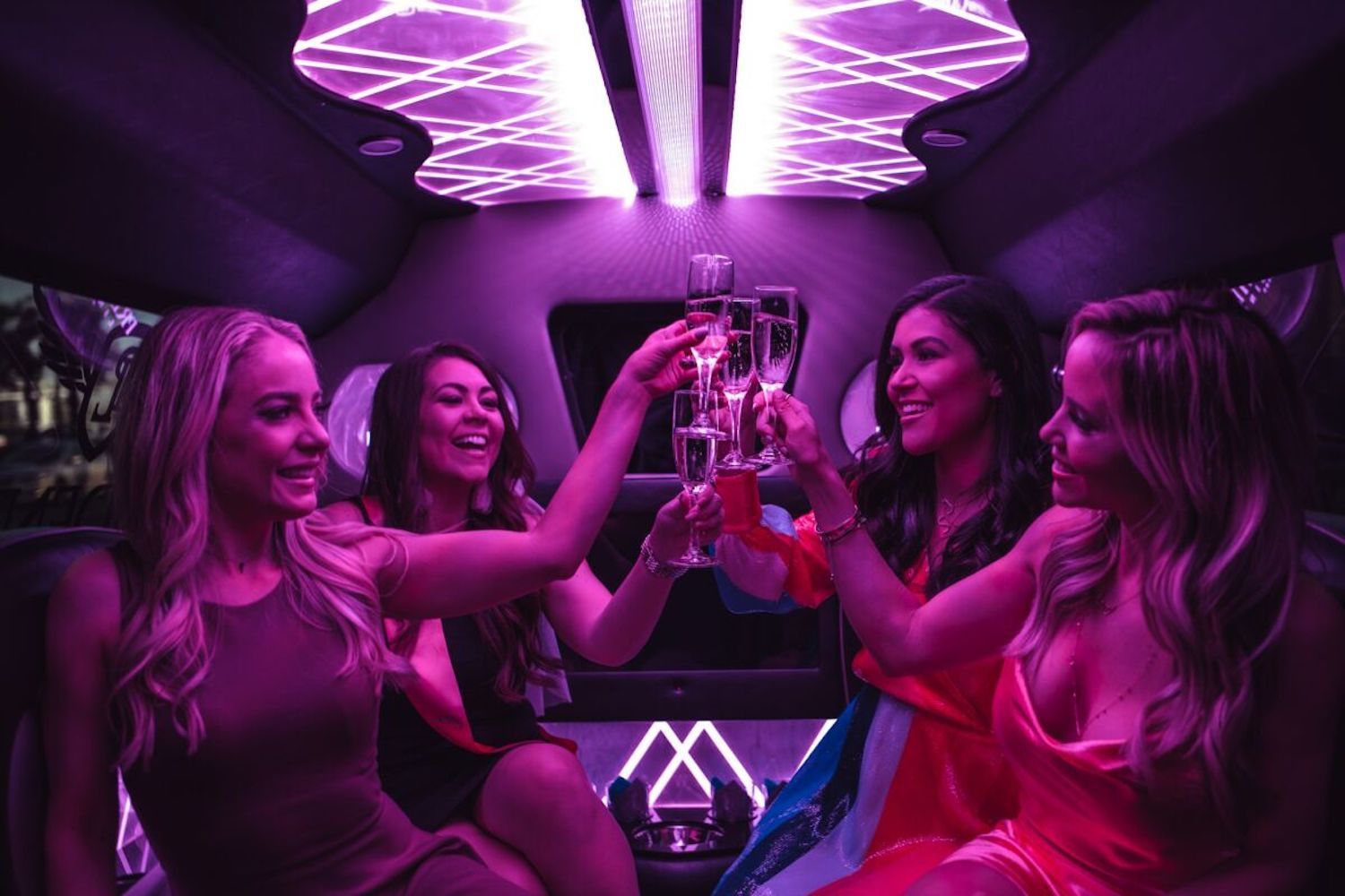 A group of women are sitting in a limousine toasting with champagne.