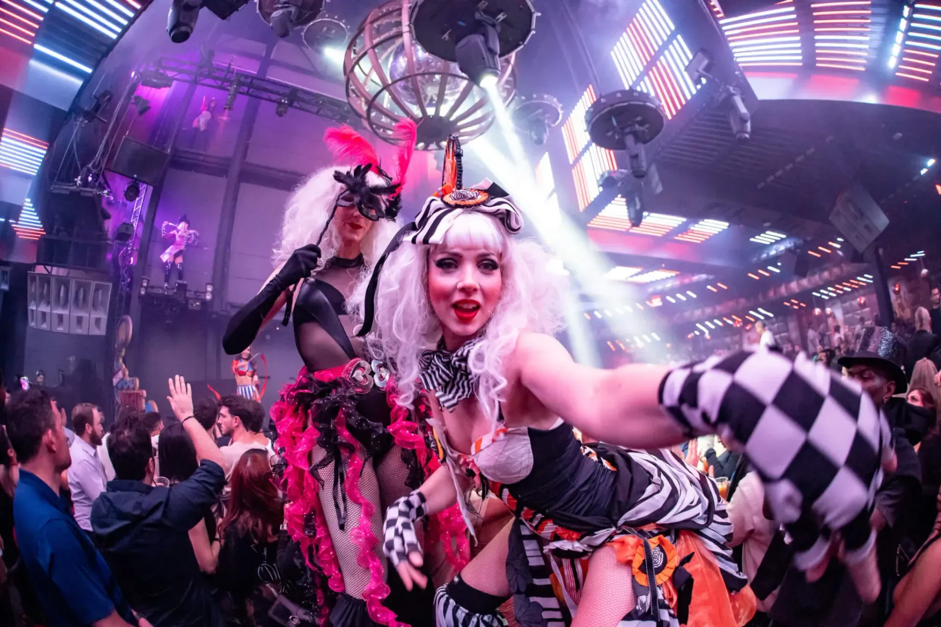 A group of women dressed in clown costumes are dancing in a club.