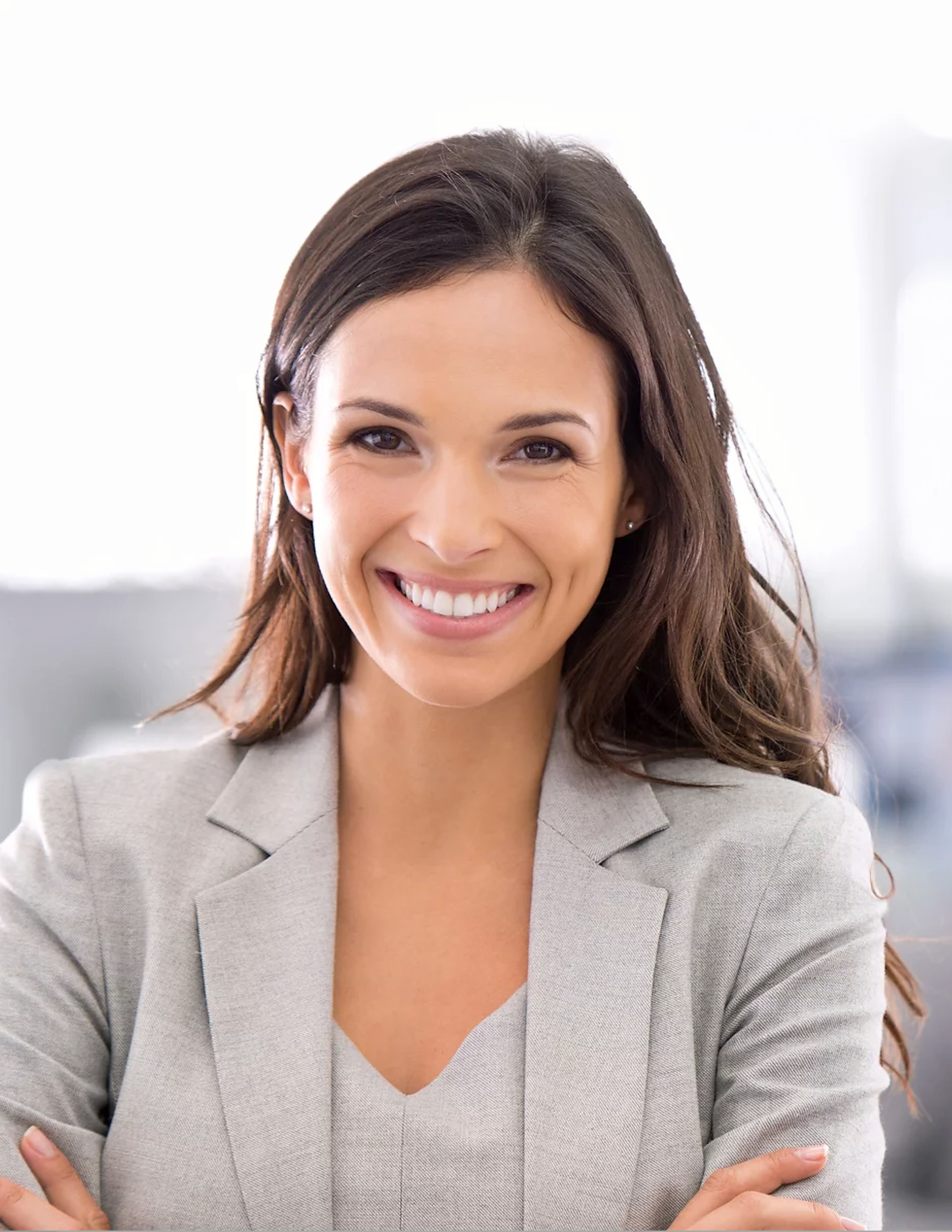 A woman in a suit is smiling with her arms crossed.