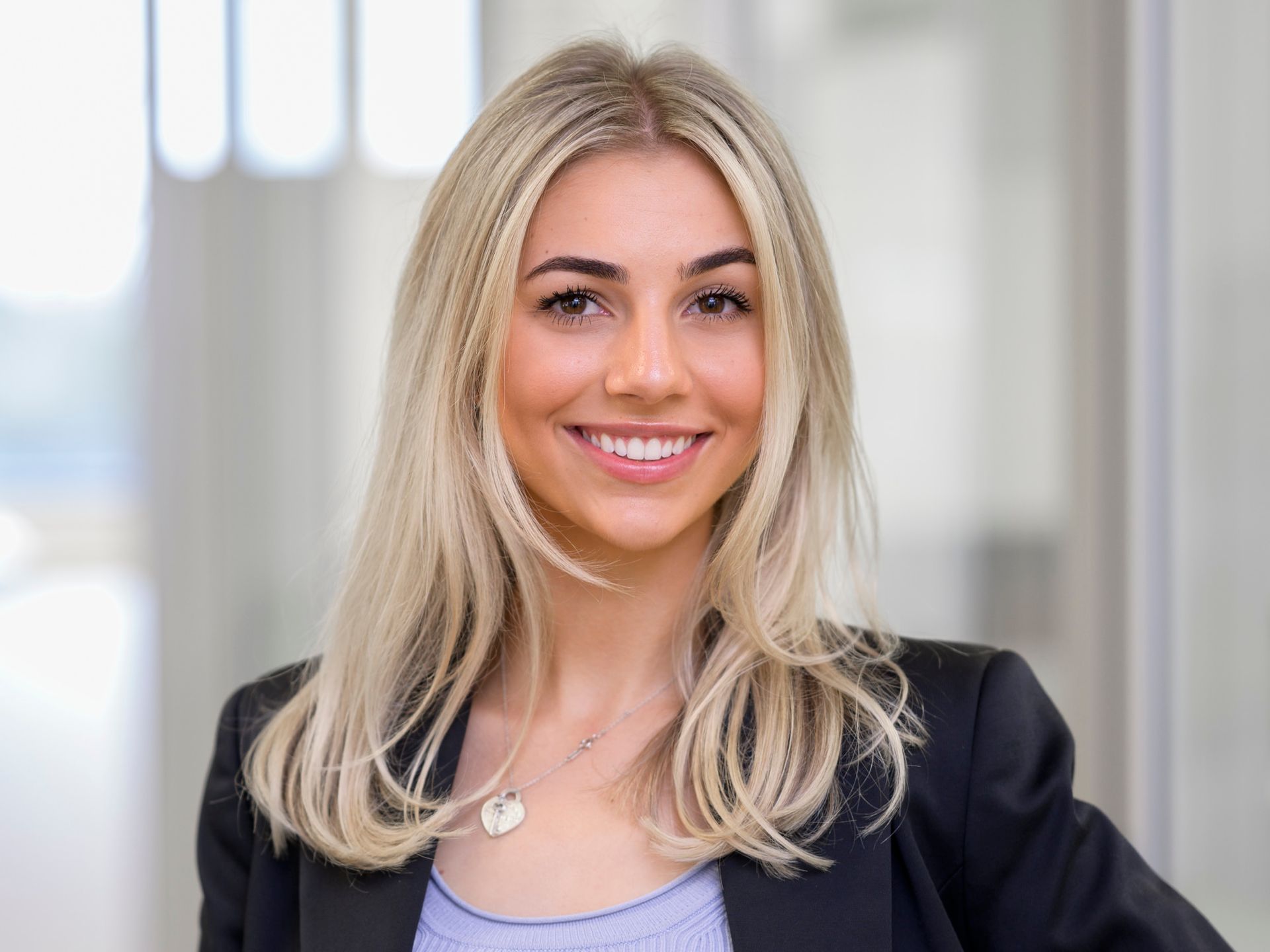 A woman with blonde hair and a black jacket is smiling for the camera.