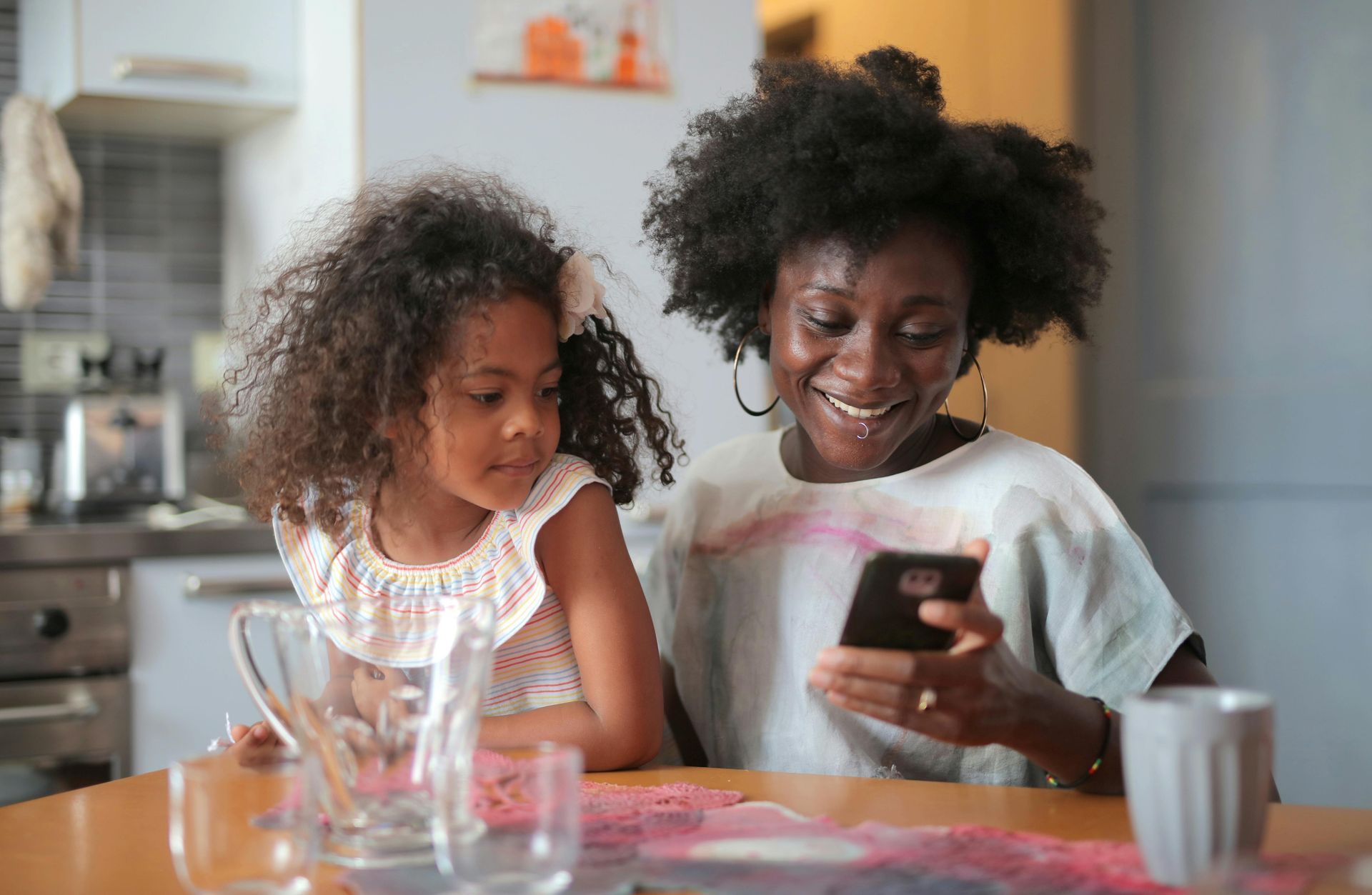Parent and child at a table looking at a phone
