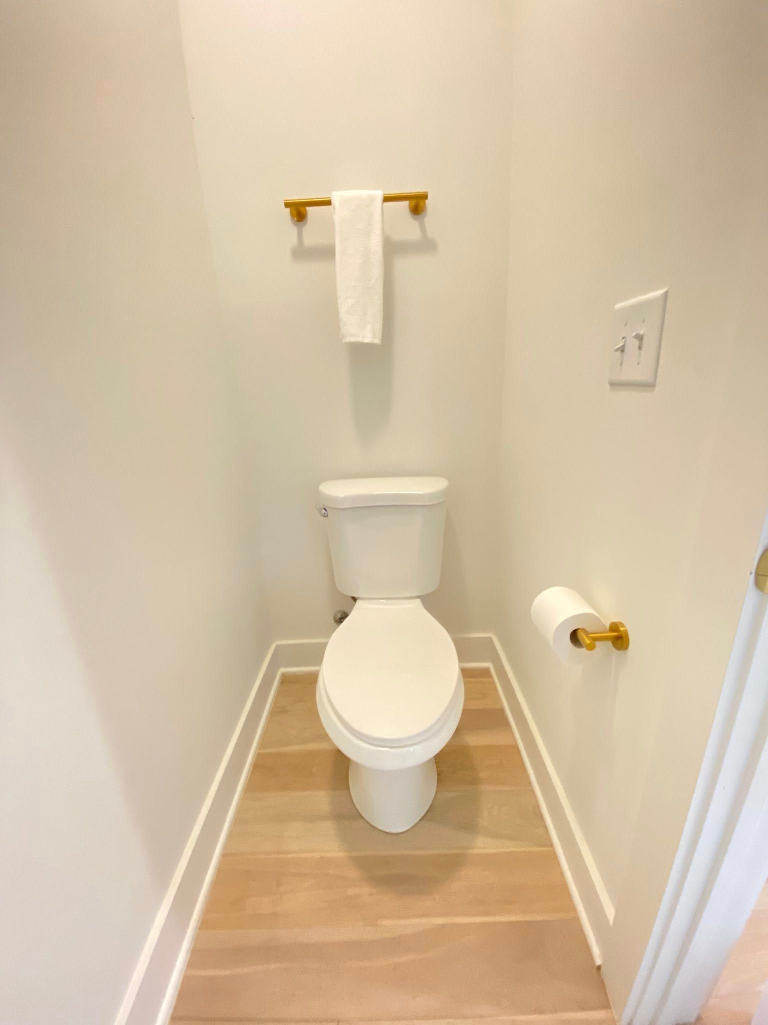 A small bathroom with a toilet and a towel rack.
