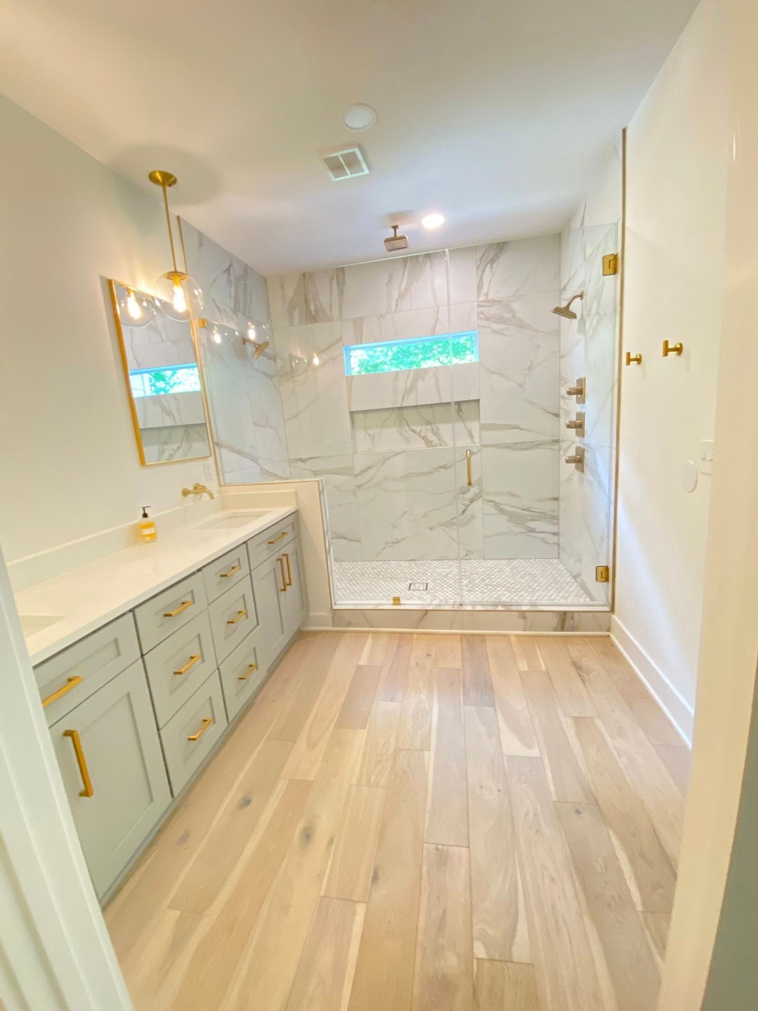 A bathroom with a walk in shower , sink and mirror.