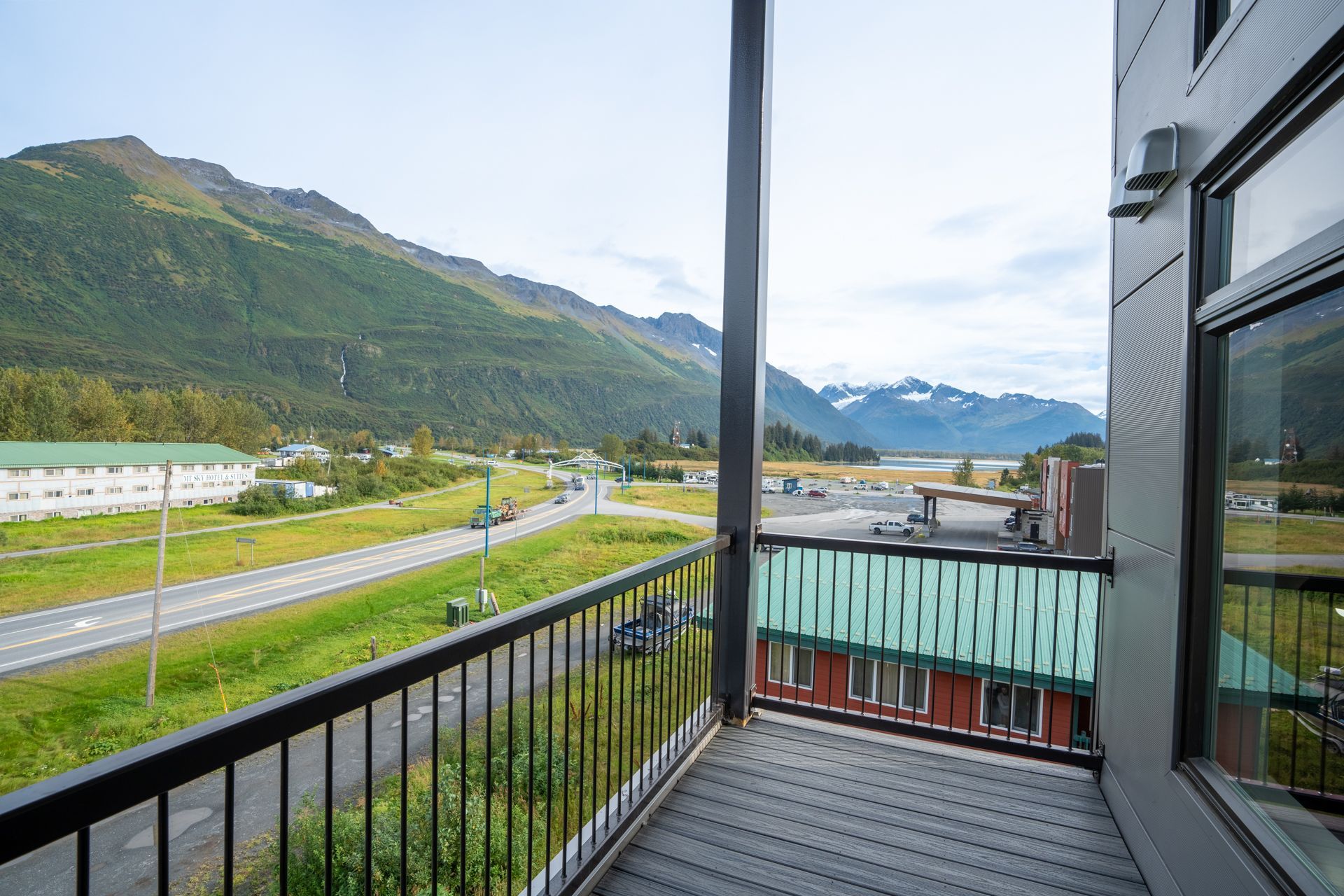 A hotel room with a bed , nightstand , television , and large windows.