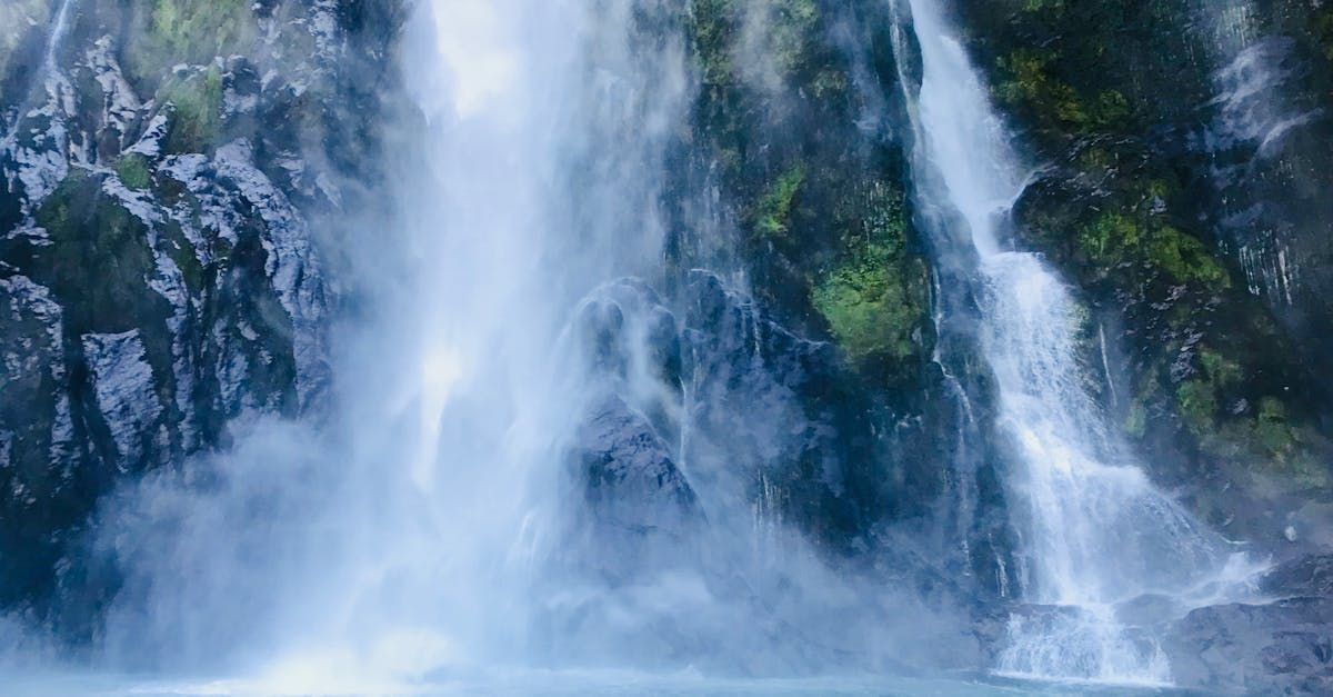 A waterfall is surrounded by trees and rocks in the middle of a forest.
