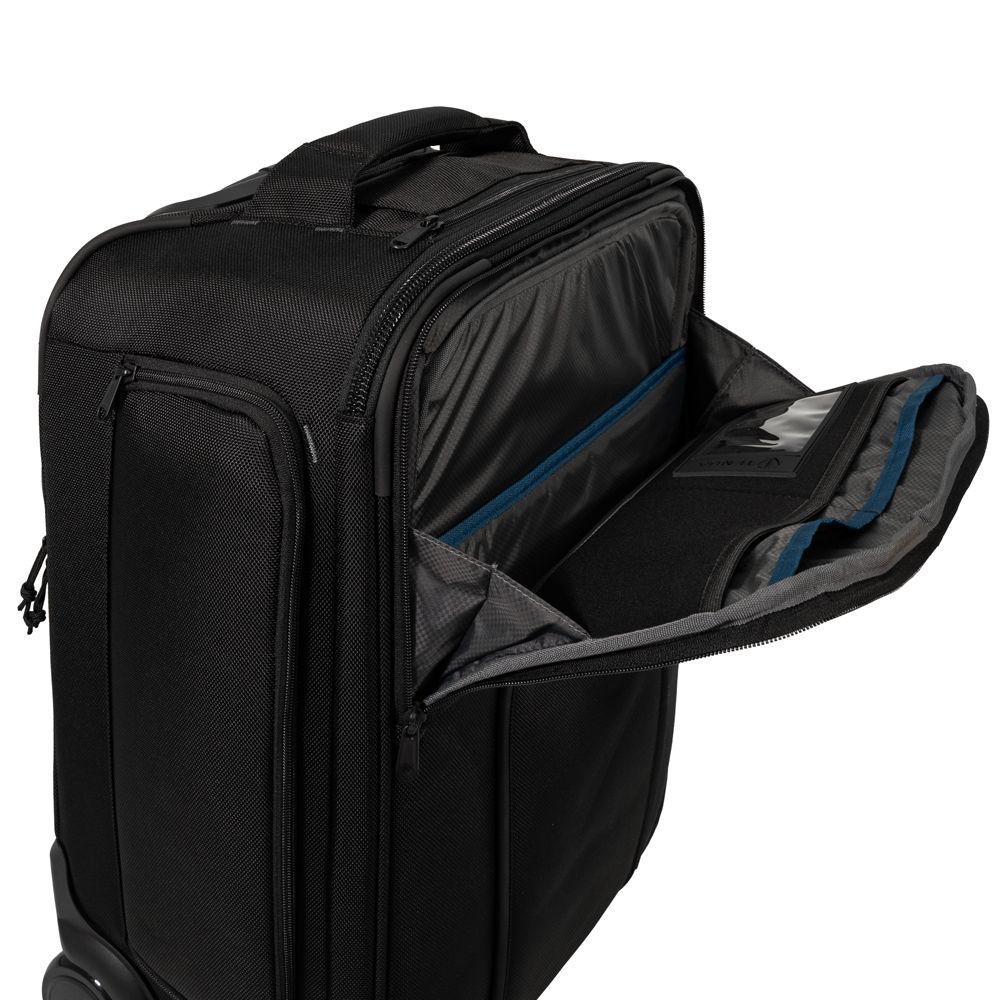 A man in a plaid shirt is carrying a black suitcase on his back