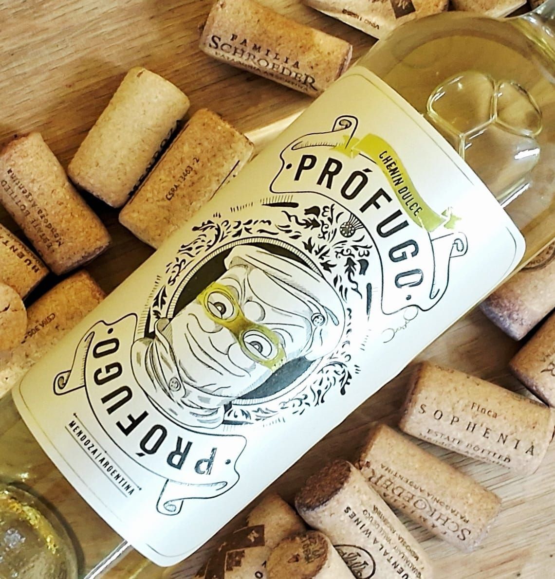 Una botella de vino blanco con etiqueta “Prófugo” que presenta una cara ilustrada, rodeada de numerosos corchos