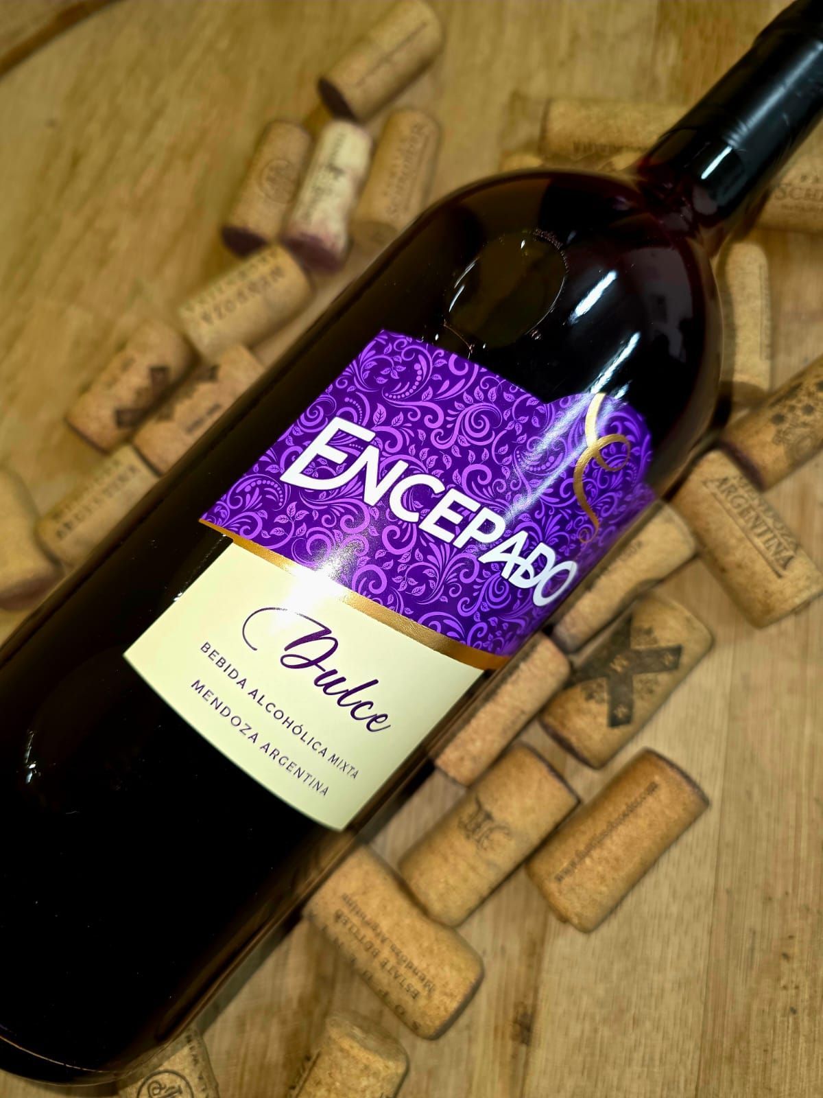 Una botella de vino Encepado Dulce rodeada de corchos de vino esparcidos sobre una superficie de madera.