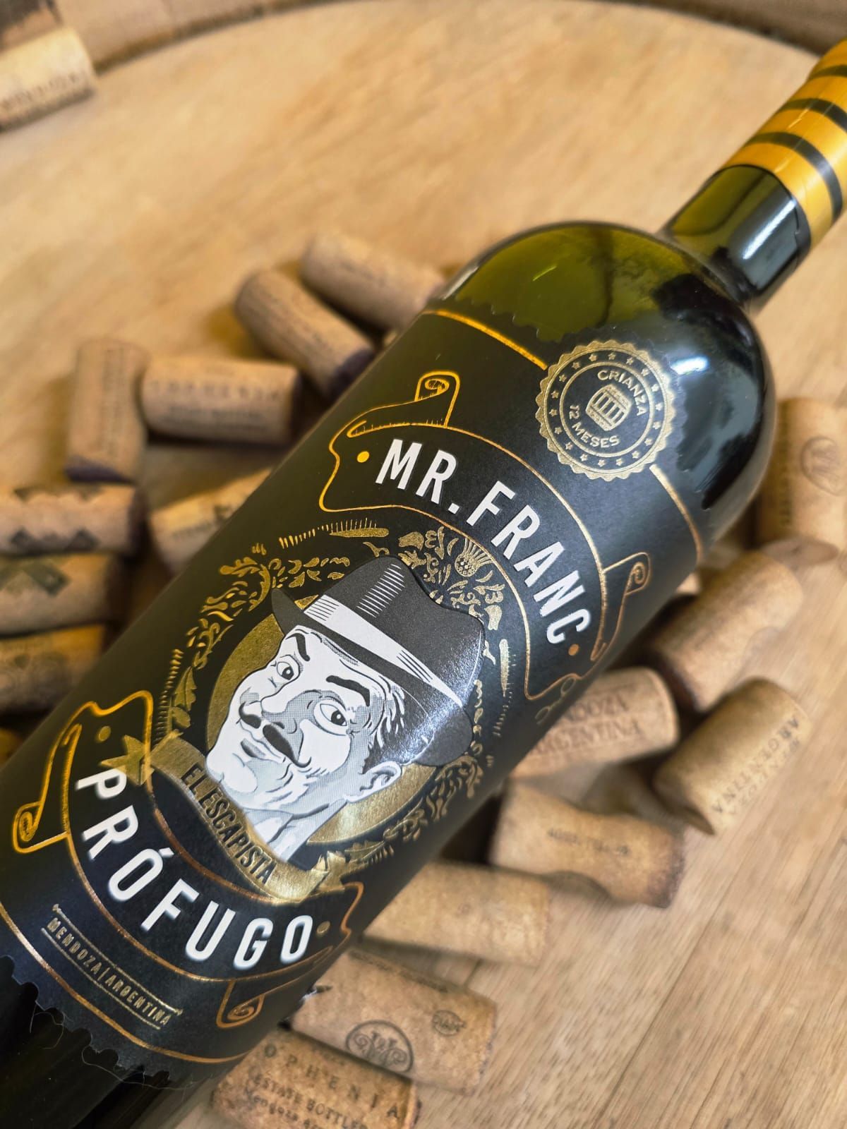 Una botella de vino Prófugo Mr. Franc descansa sobre una pila de corchos sobre una superficie de madera.