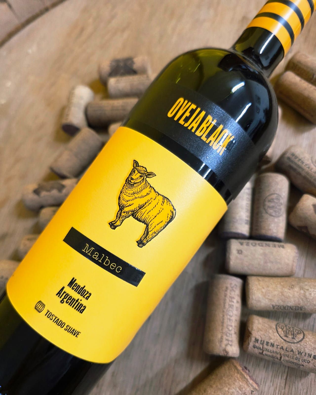 Una botella de vino Oveja Black Malbec de Mendoza, Argentina, colocada sobre una superficie de madera