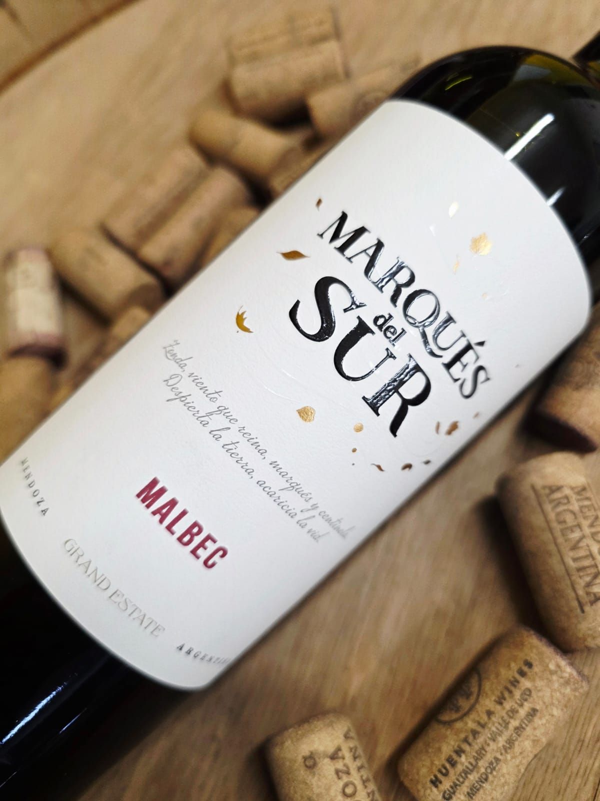 Una botella de vino Marqués del Sur Malbec descansando sobre una pila de corchos.