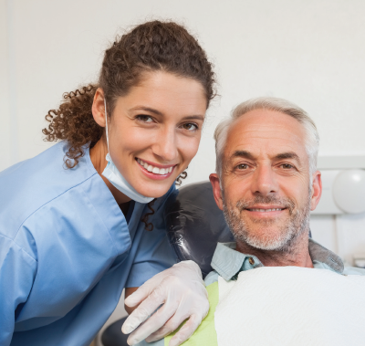 Dentist and patient smiling in dental office setting.