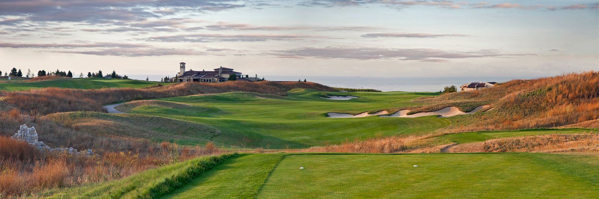 A painting of a golf course with a church in the background.