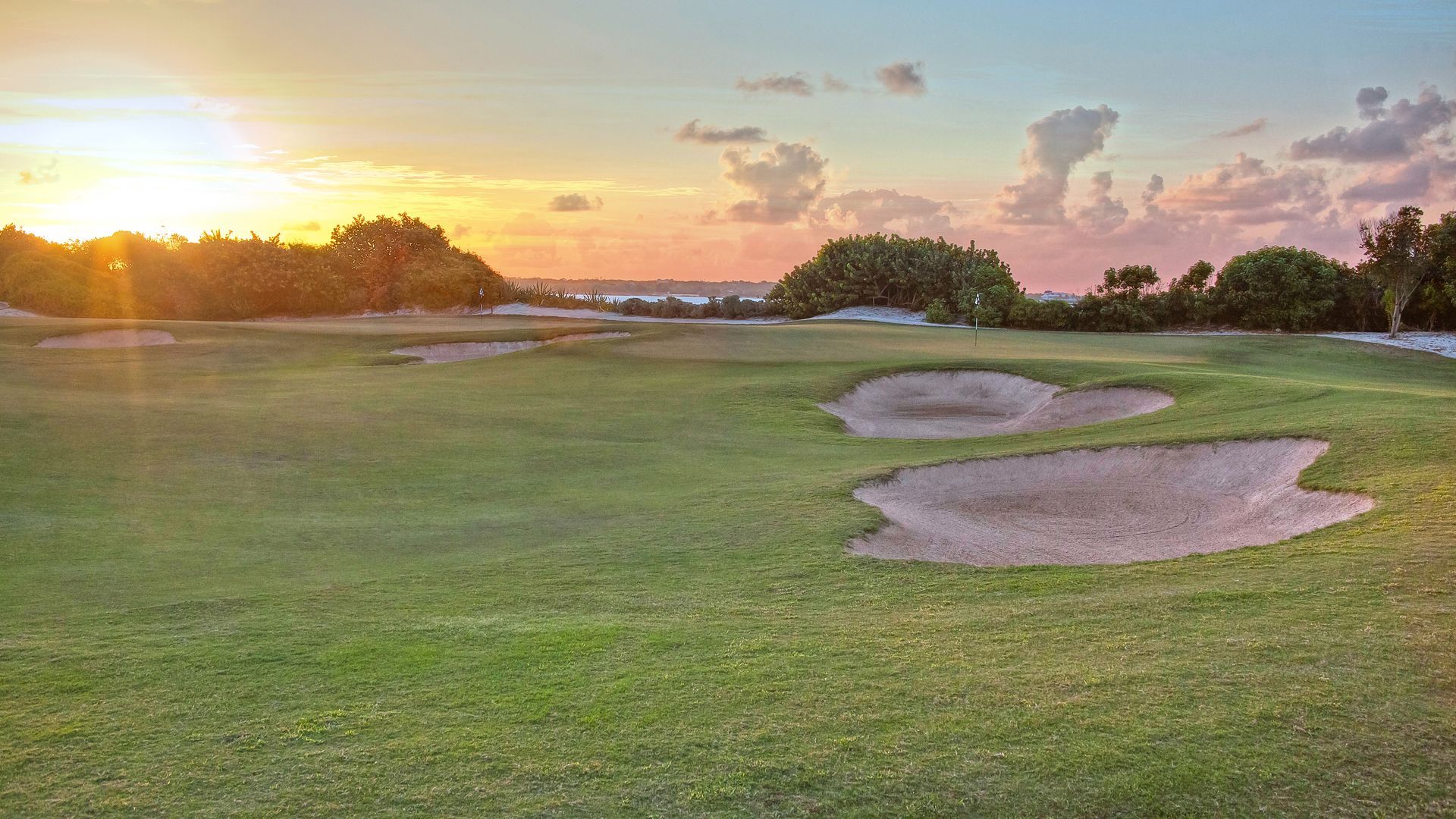 A golf course with a sunset in the background