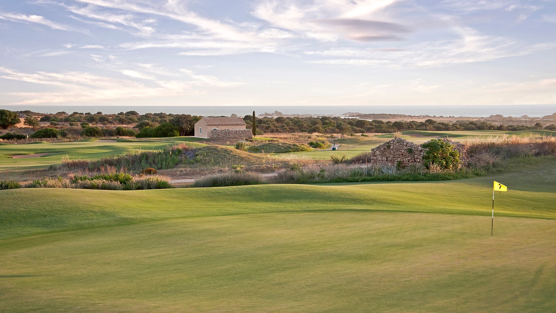 A golf course with a yellow flag in the middle of it