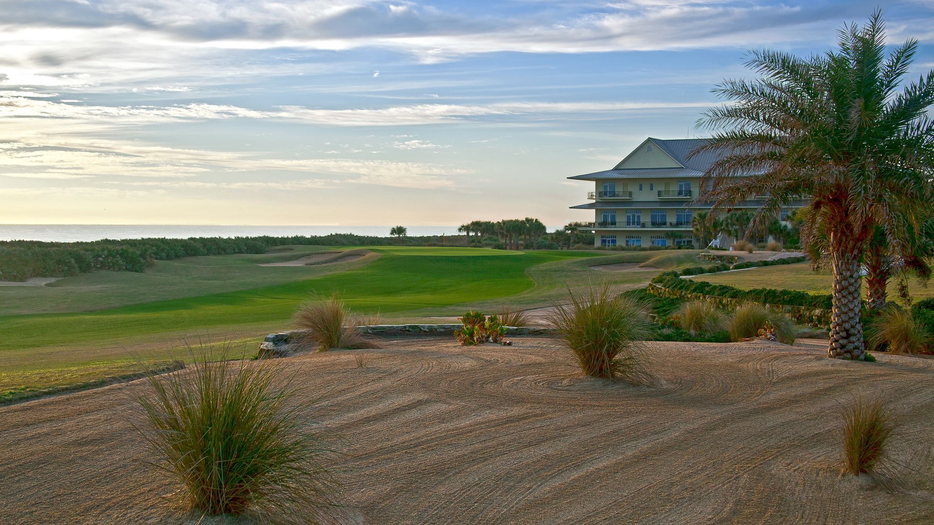 A large house is sitting on top of a hill overlooking a golf course.