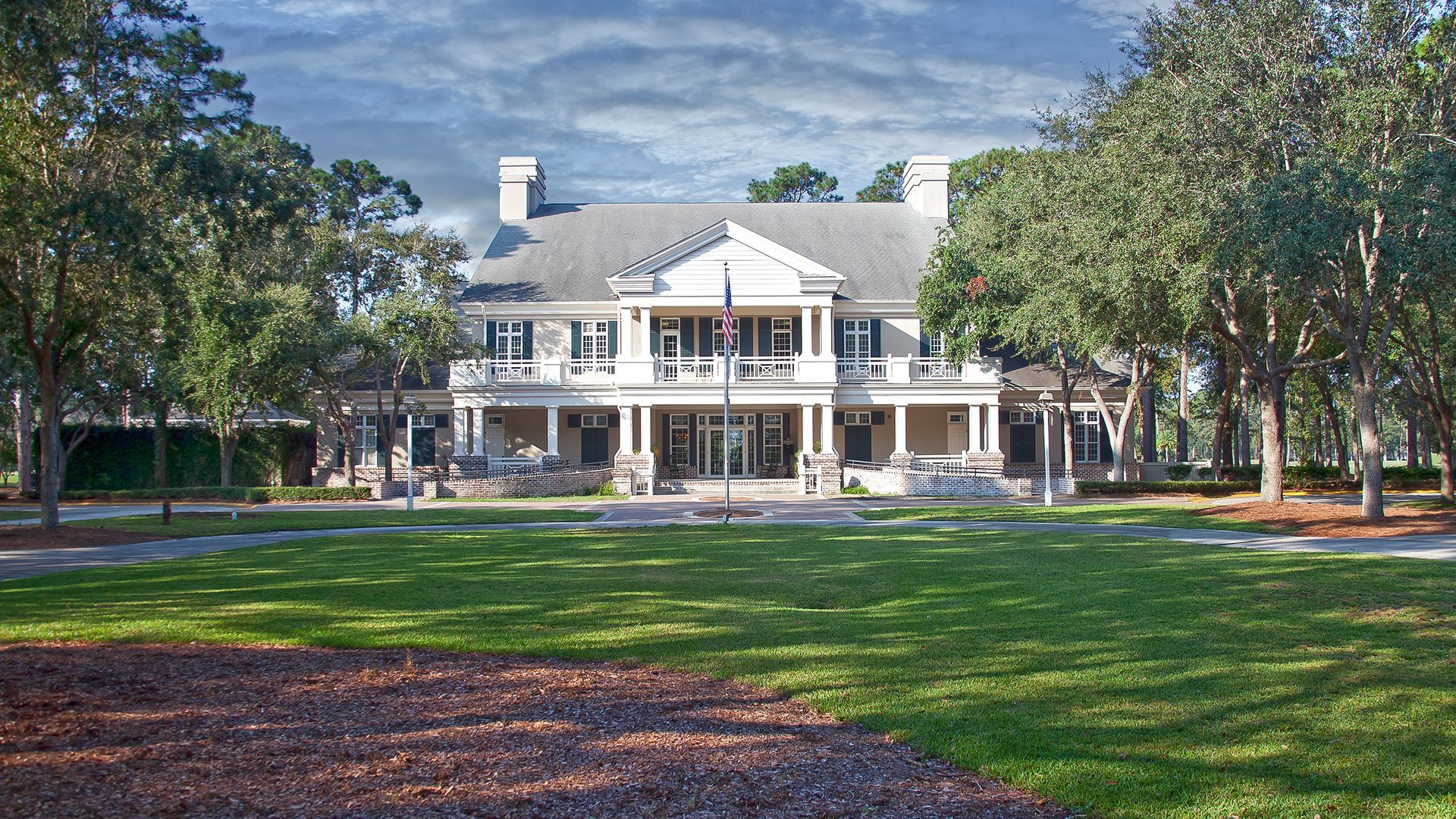 A large white house is surrounded by trees and grass.
