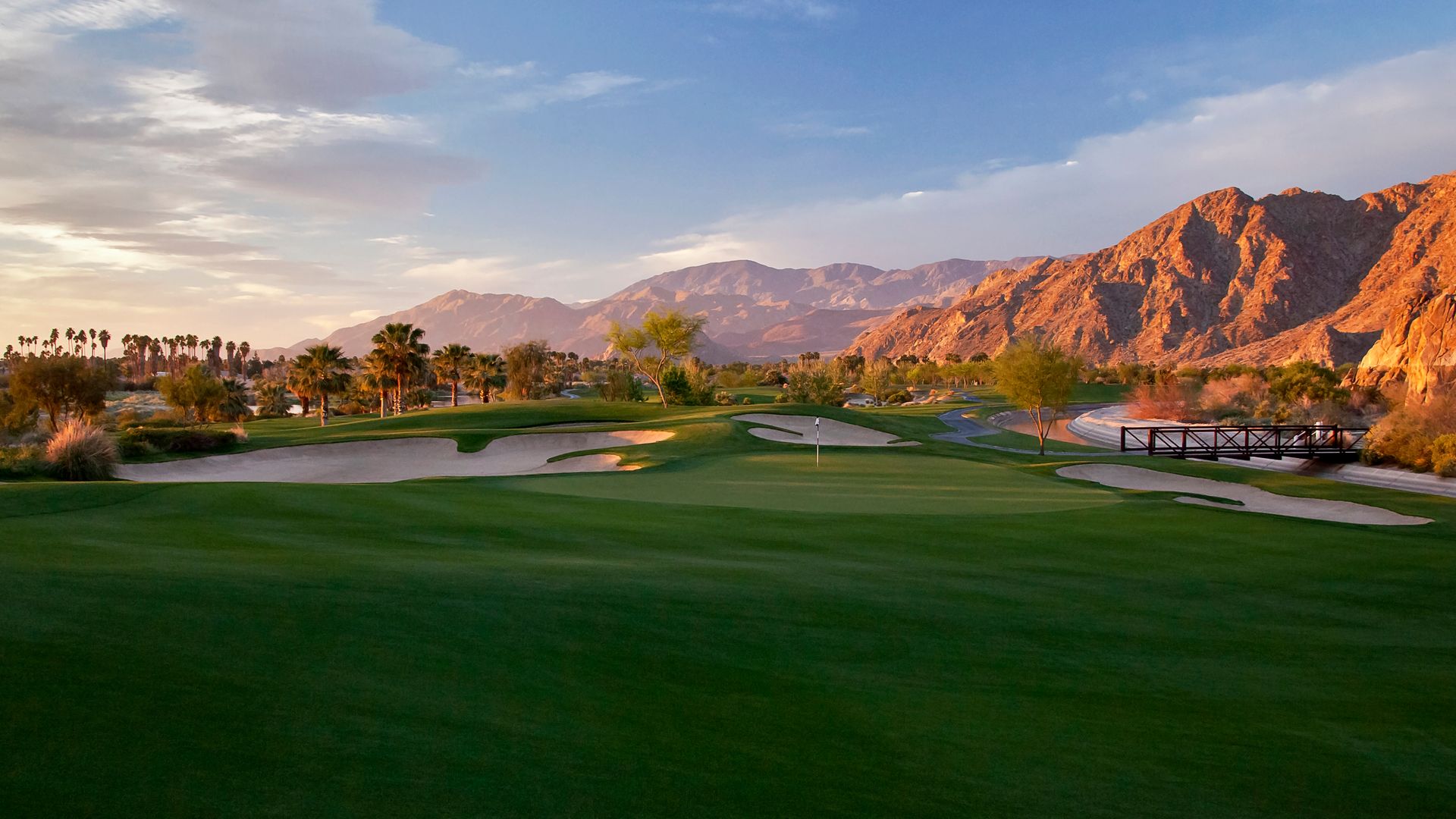 A golf course with mountains in the background and a bridge in the middle