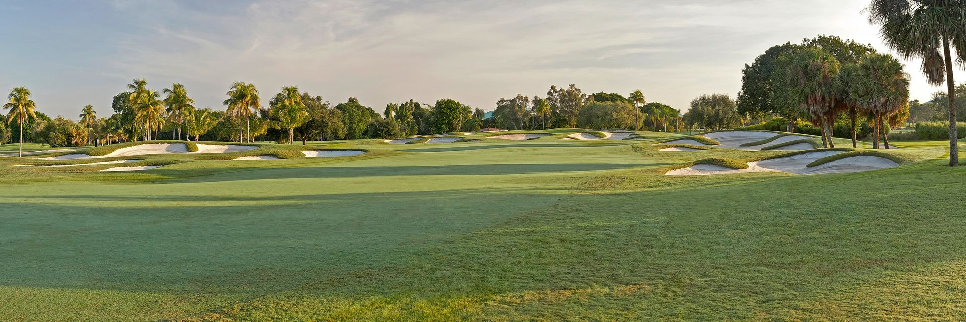 A panoramic view of a golf course with trees in the background