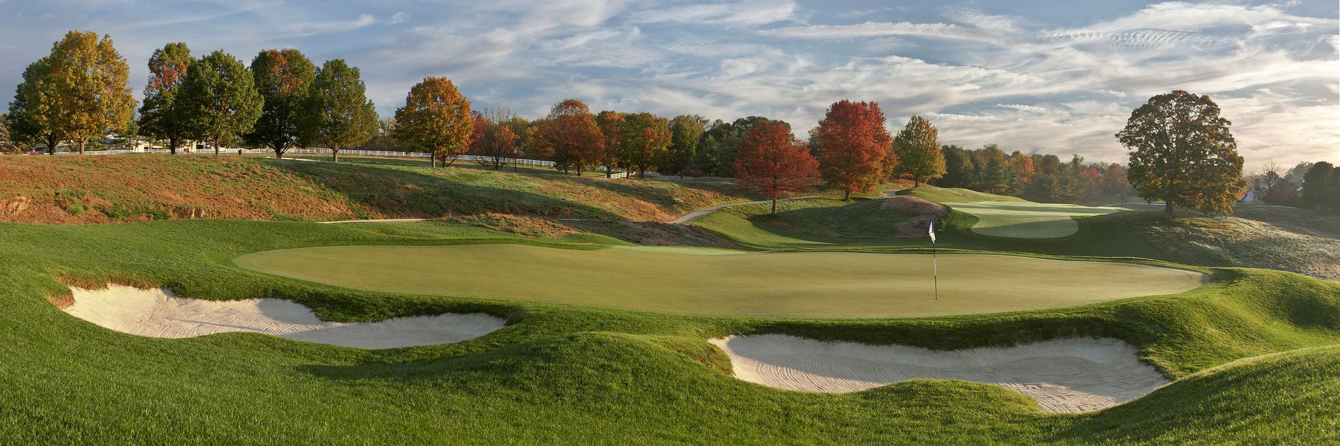 An artist 's impression of a golf course with trees in the background.