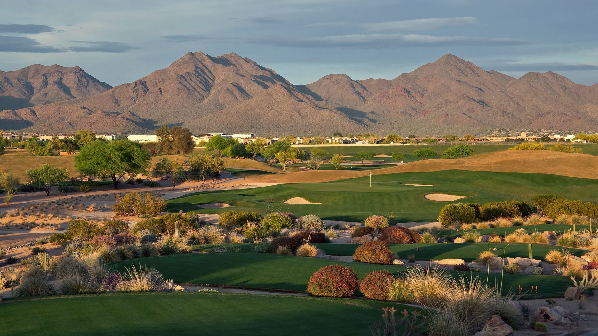 A golf course in the desert with mountains in the background