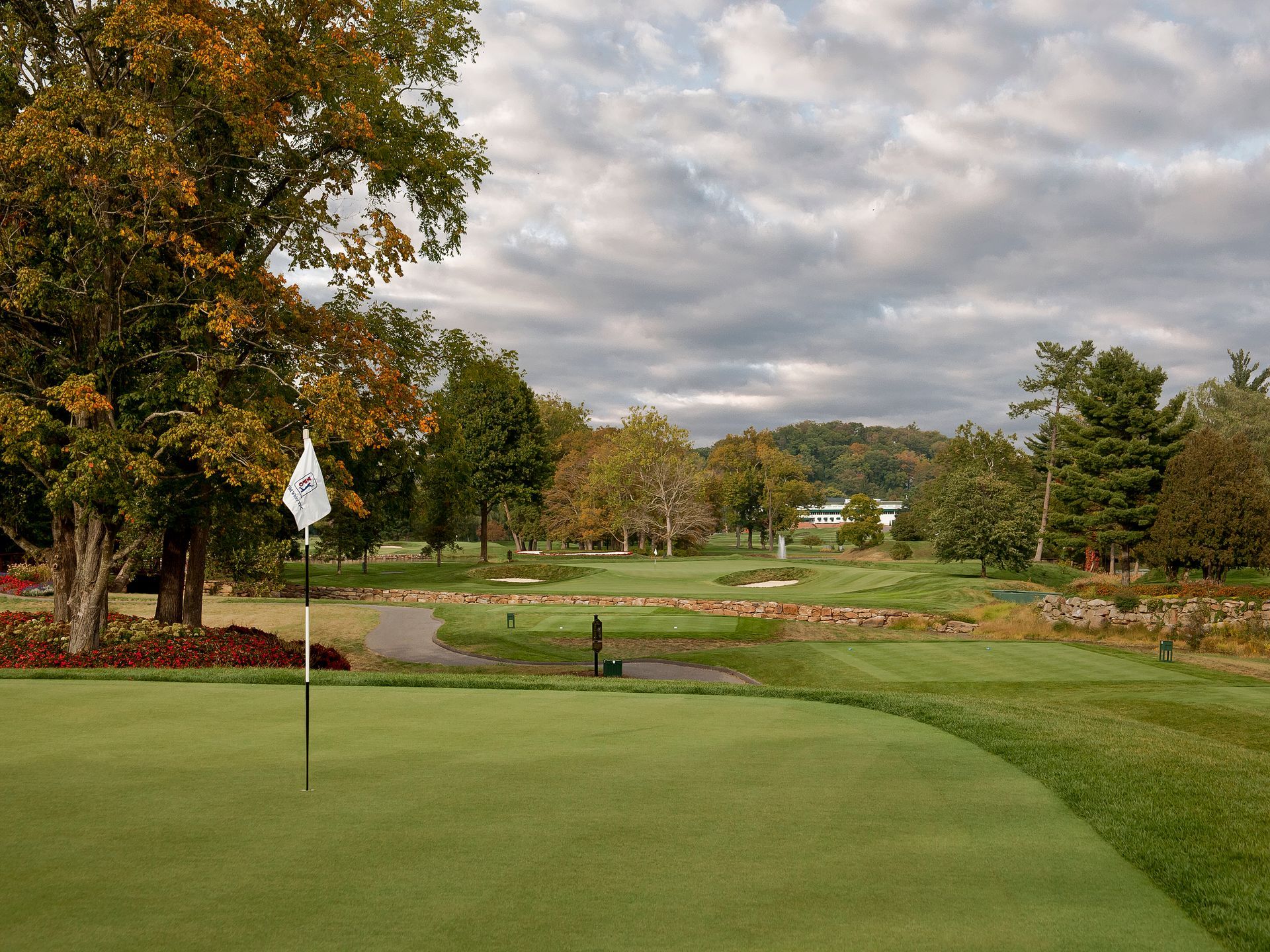 A golf course with a green and trees in the background