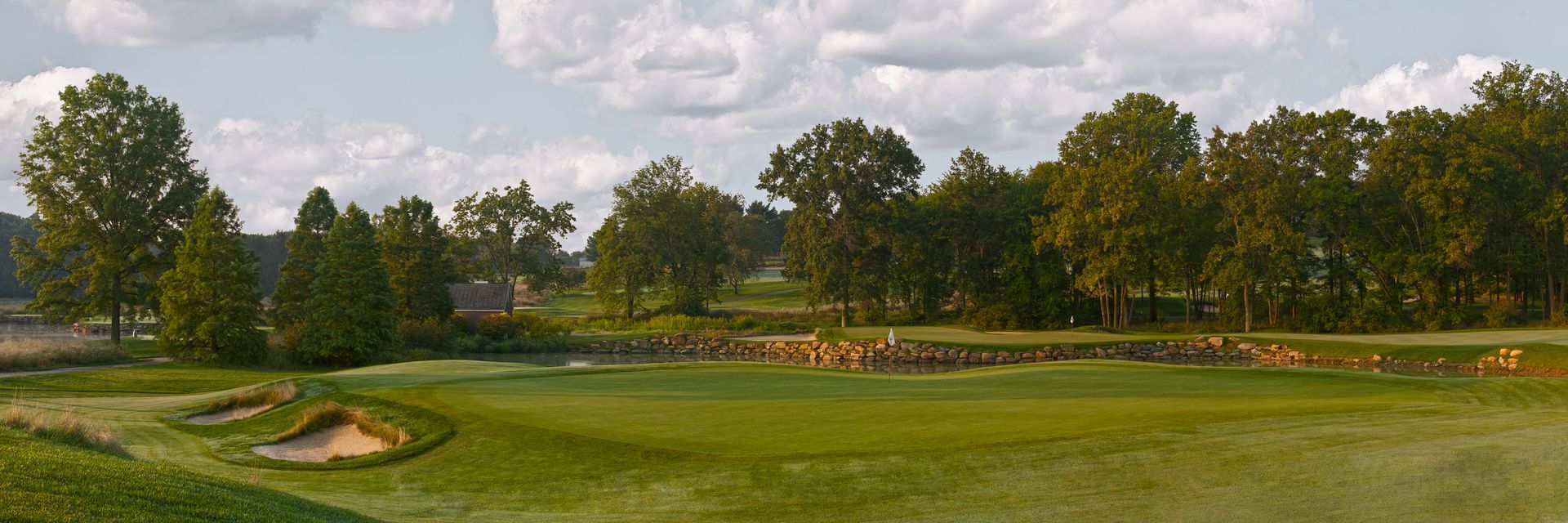 A golf course with trees and a pond in the background