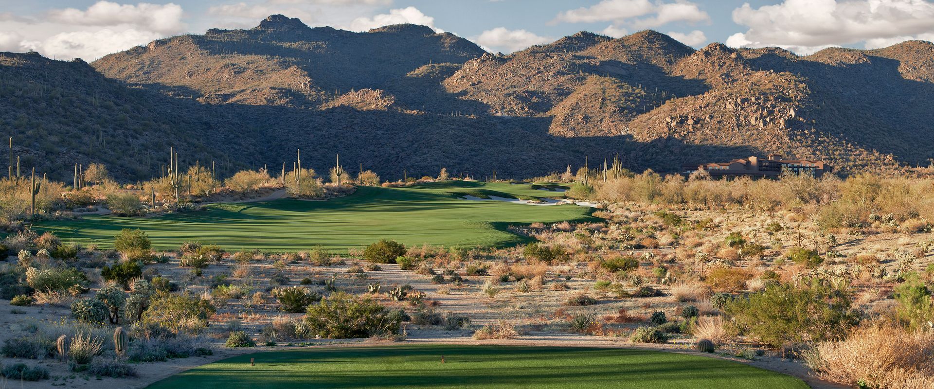 A golf course in the desert with mountains in the background