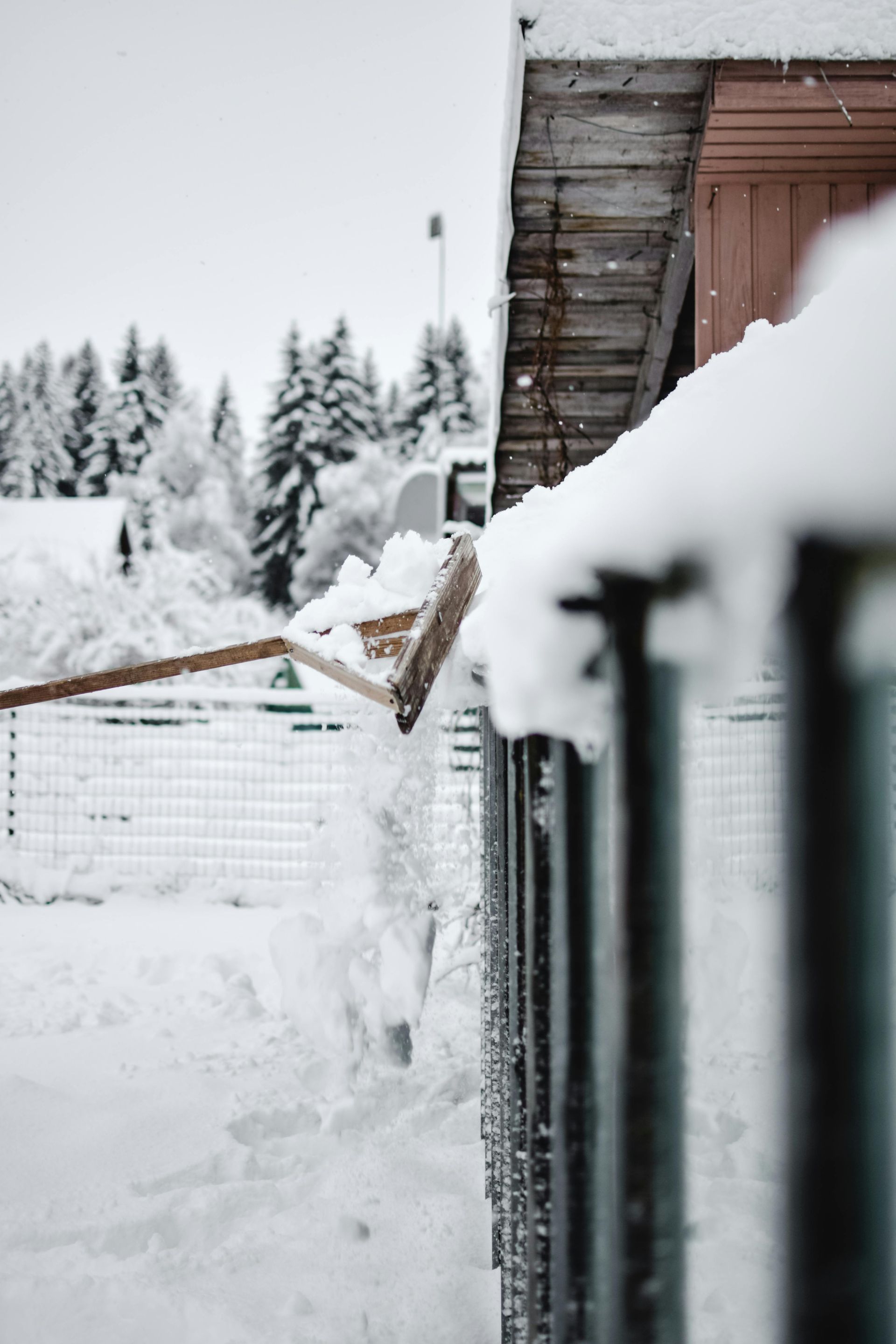 A person is shoveling snow from the roof of a building.