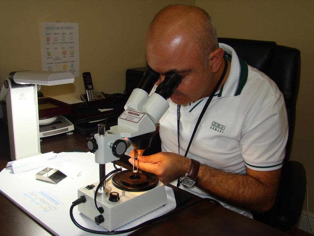 Man using a microscope to examine an object, likely in a lab or office setting.