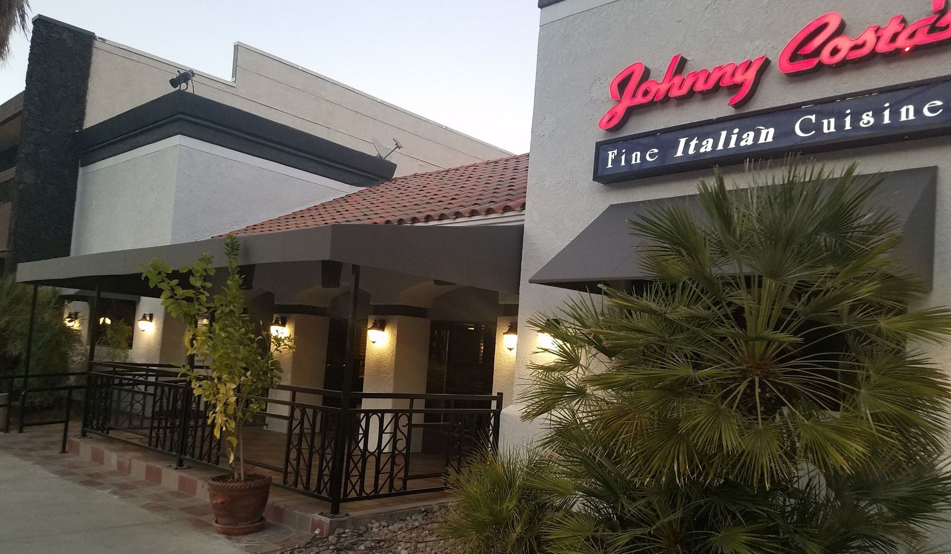 A white building with a red sign that says johnny costa 's