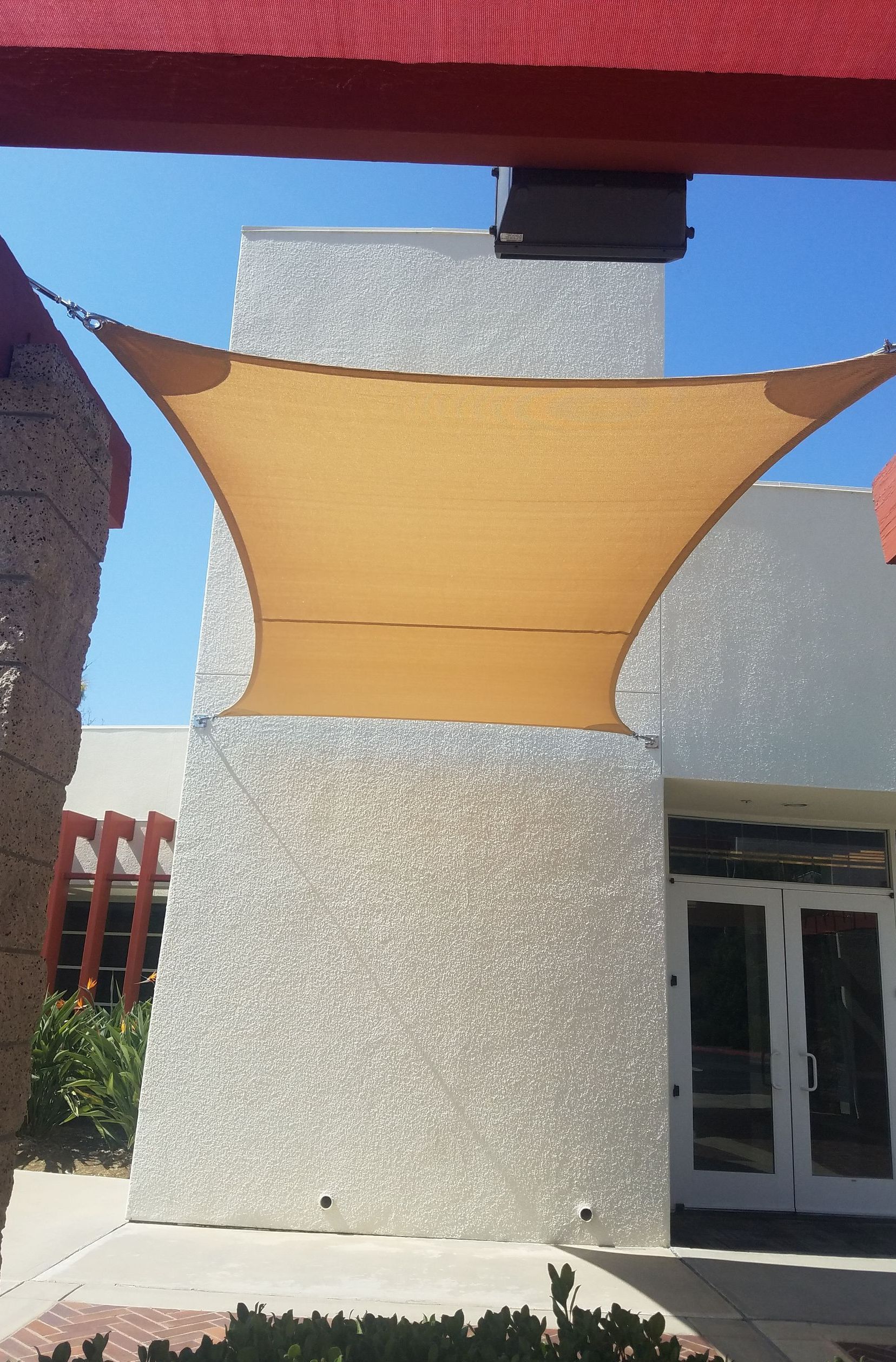 A large shade sail is hanging from the side of a building