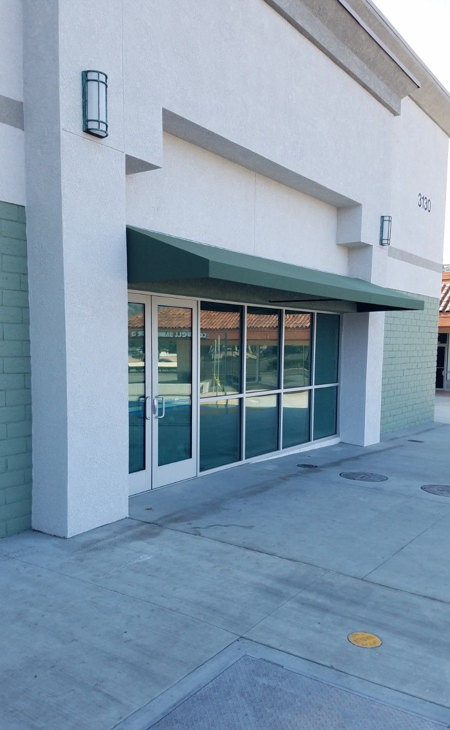 A white building with a green awning over the door.