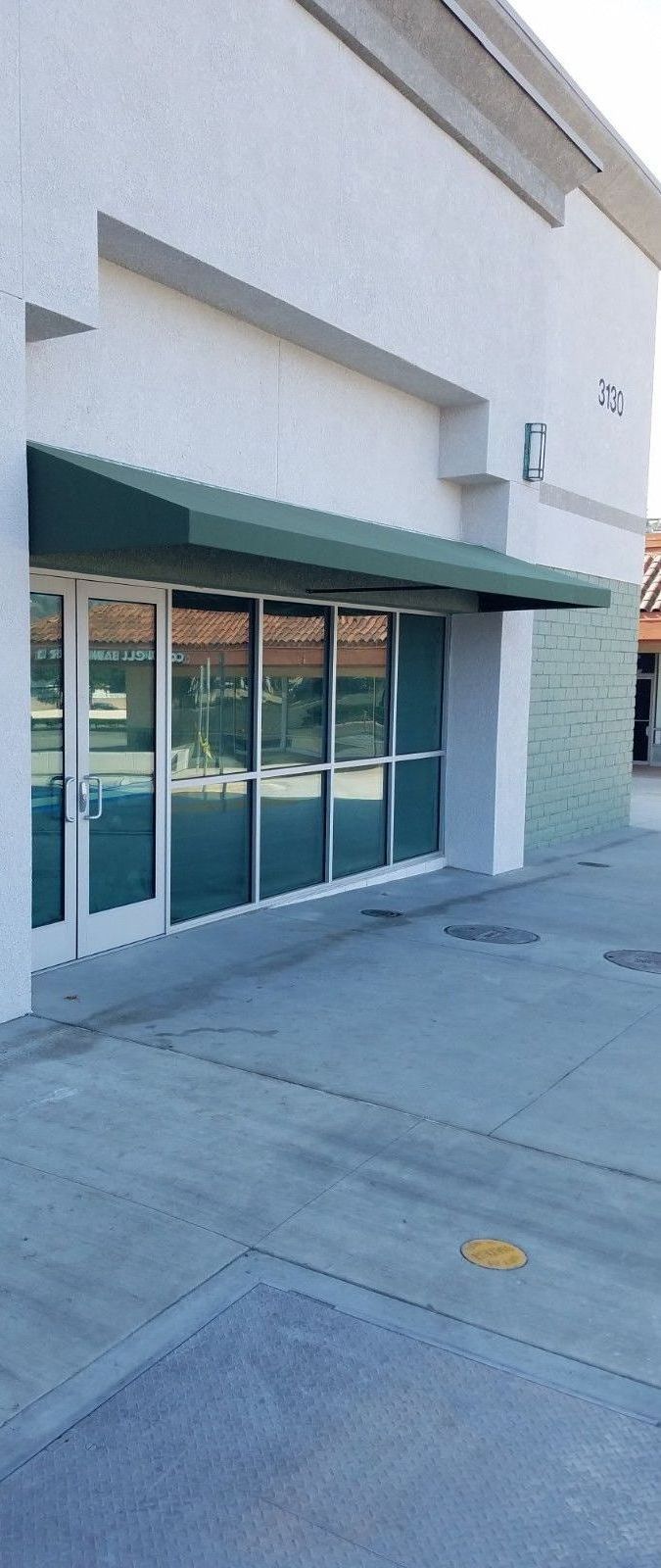 A white building with a green awning over the door.