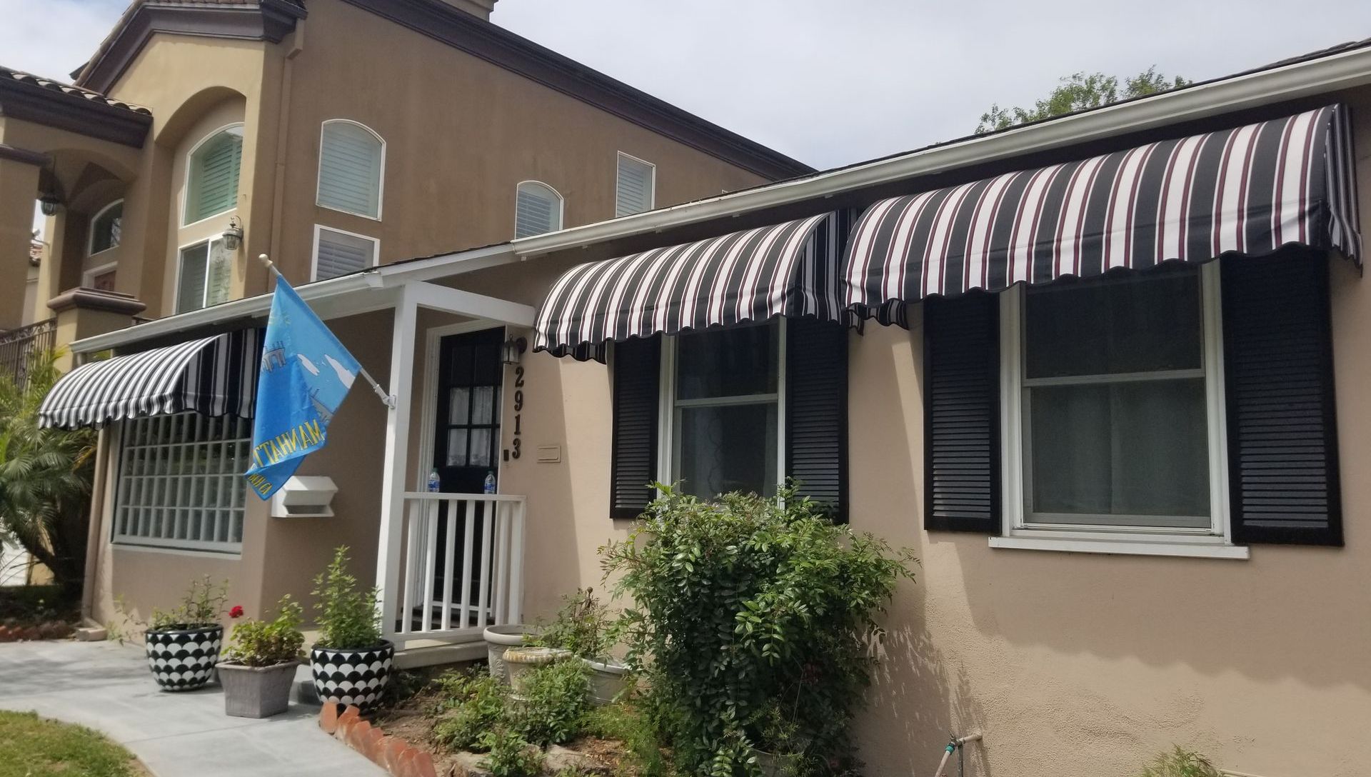 A house with a black and white awning on the windows