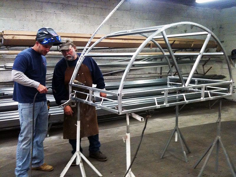 Two men are working on a metal structure in a factory