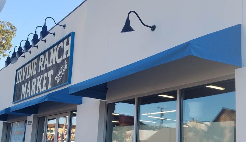 A white building with a blue awning and a sign that says ranch market.