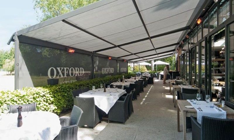 A restaurant with tables and chairs under an awning and a sign that says oxford