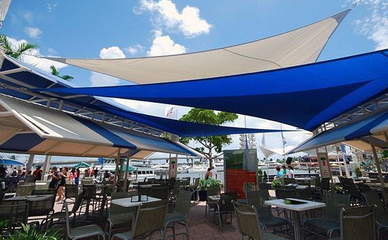 A restaurant with tables and chairs under a blue and white umbrella.