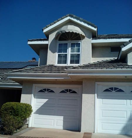 A house with two white garage doors and a large window