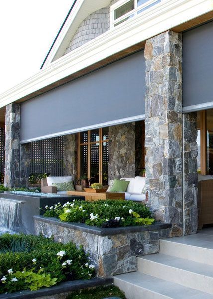 A house with a stone wall and a porch with a couch and chairs