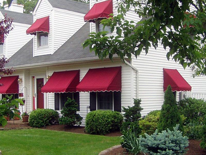 A white house with red awnings on the windows