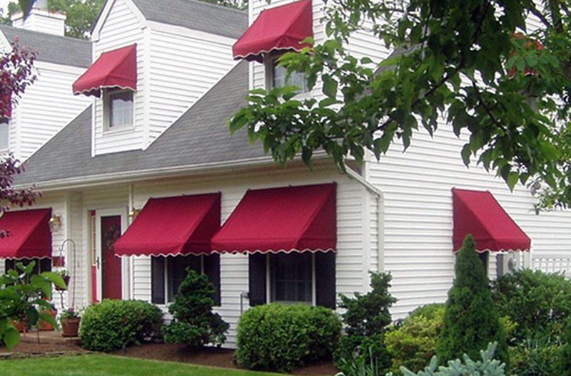 A white house with red awnings on the windows