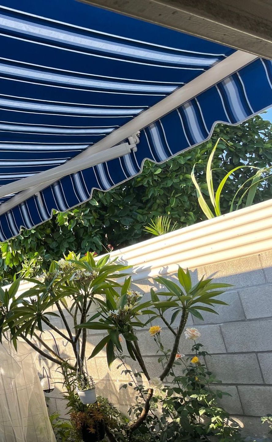 A blue and white striped awning is hanging over a patio.