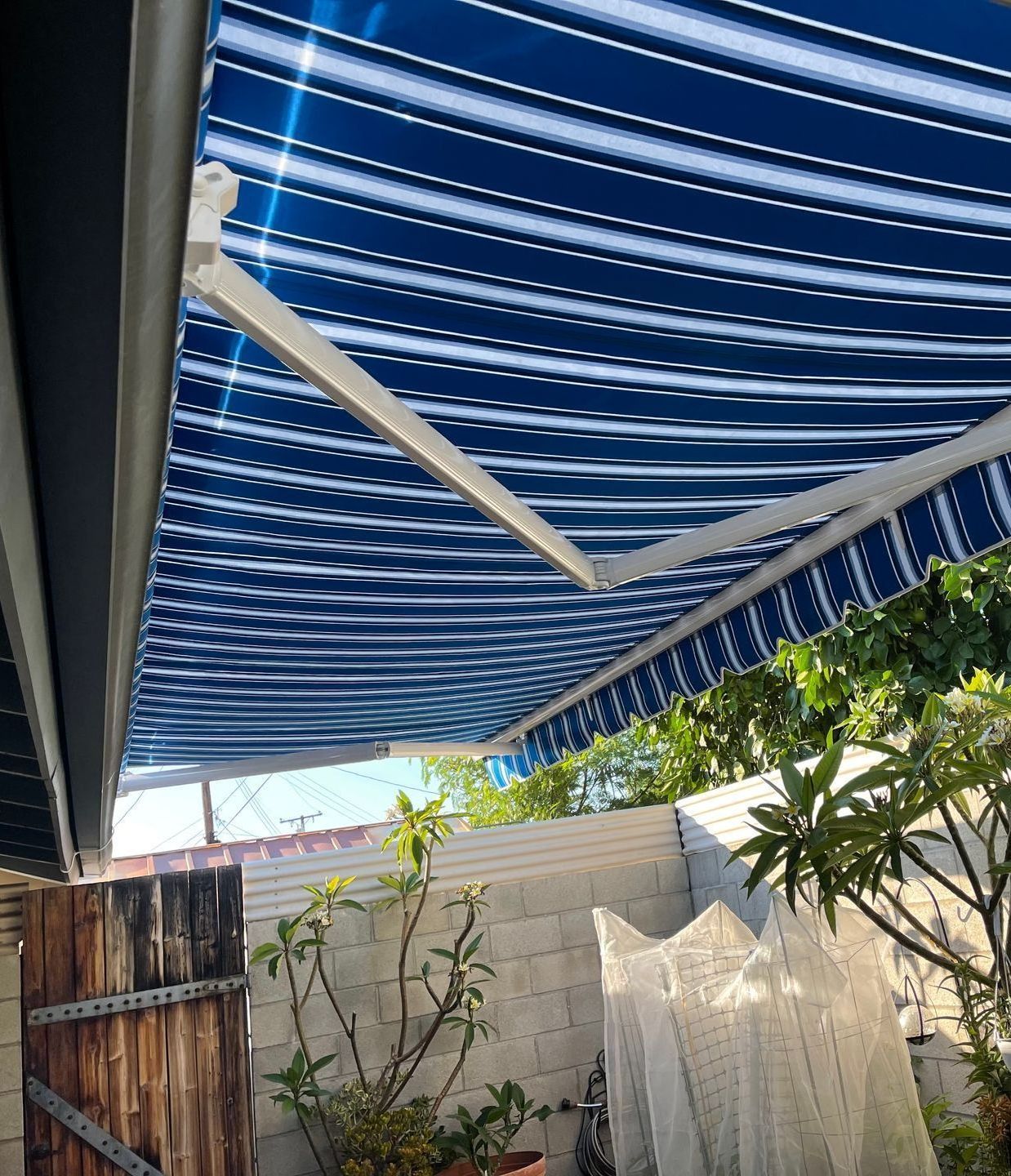 A blue and white striped awning is covering a patio.