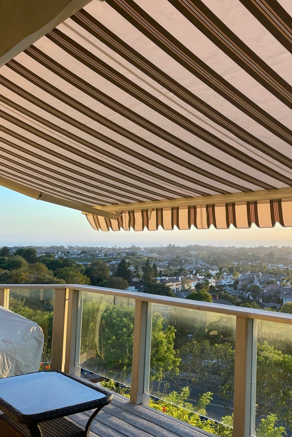 A balcony with a striped awning and a view of a city.