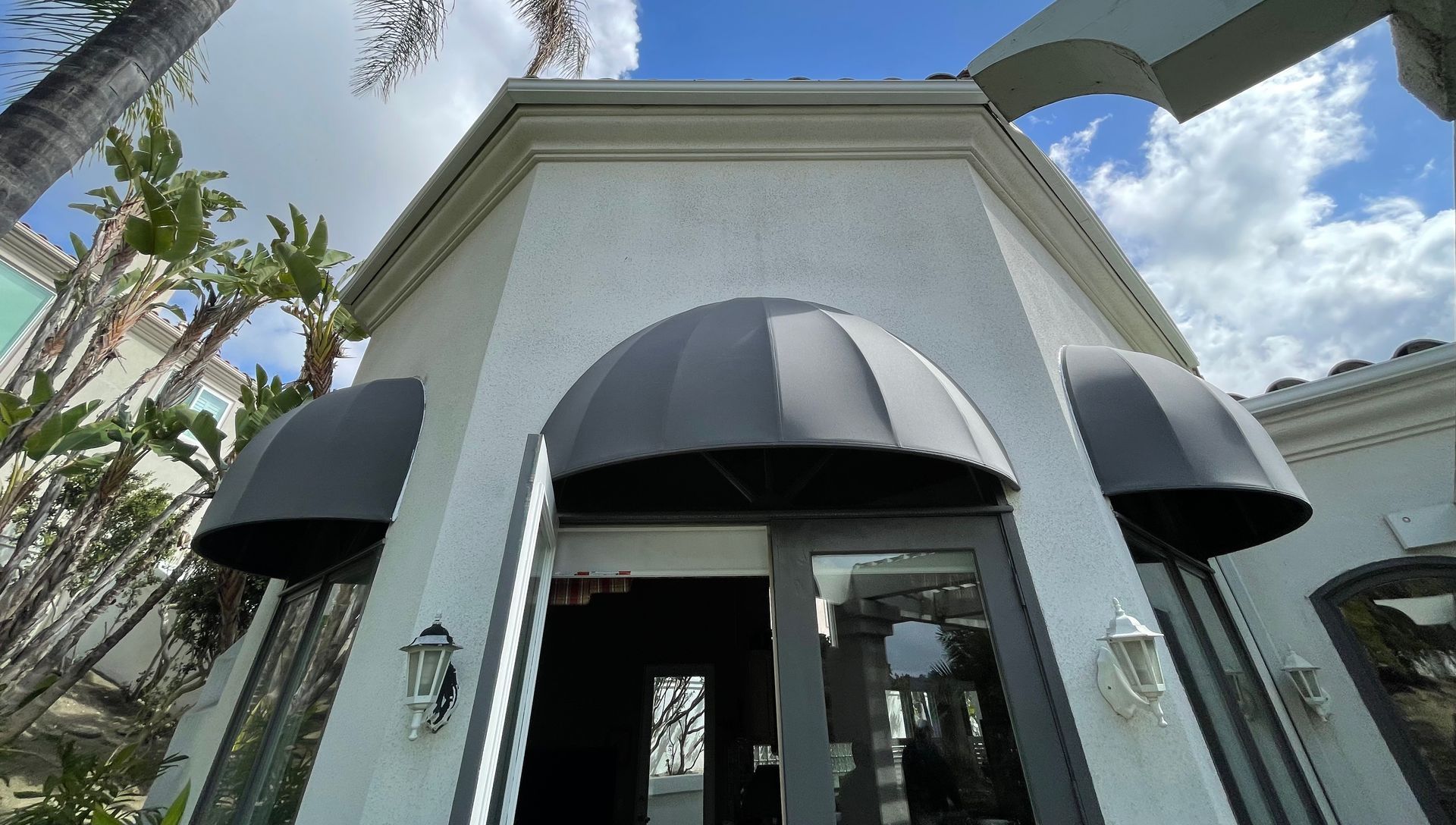 A white building with a black awning over the door.