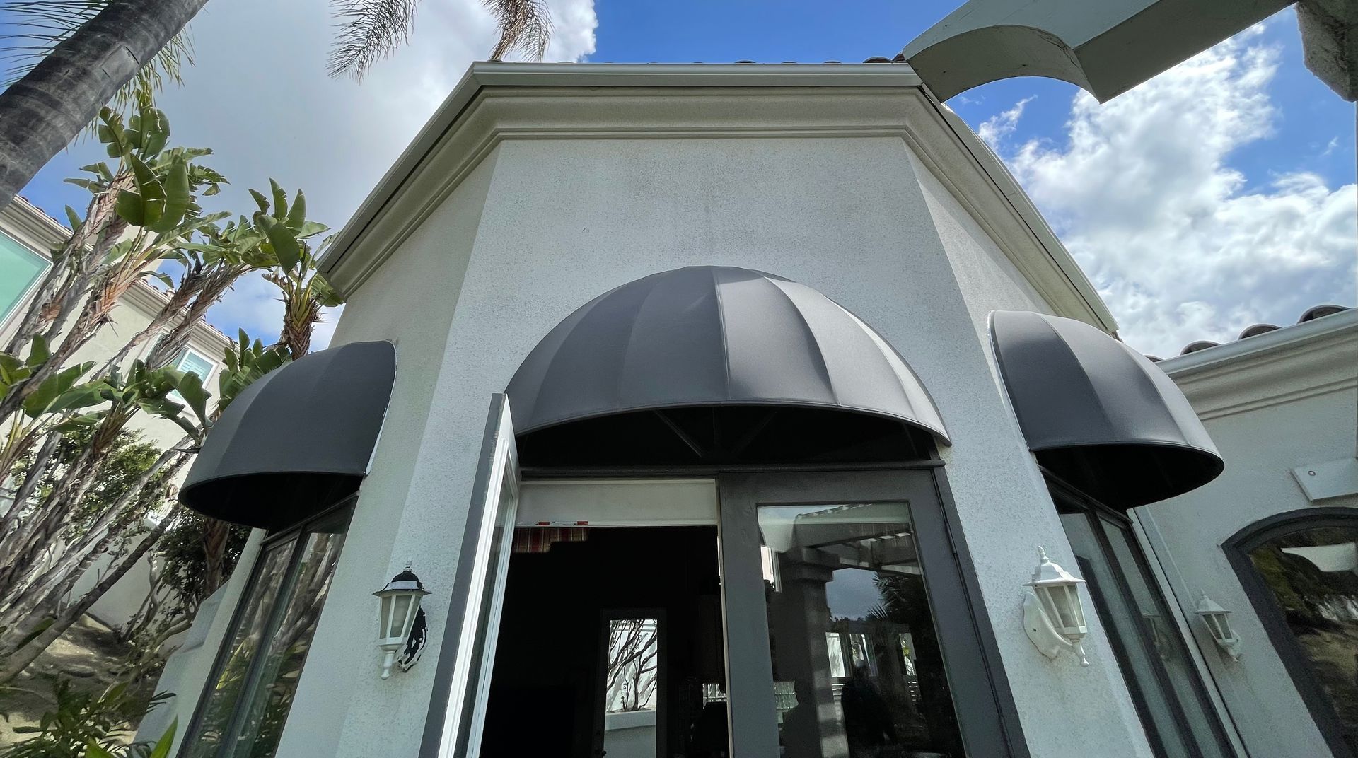 A white building with a black awning over the door.