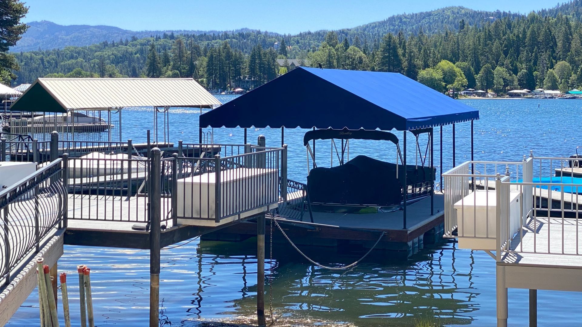 A boat is docked at a dock on a lake with mountains in the background.